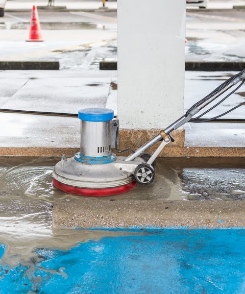 Asian worker cleaning sand wash exterior walkway using polishing machine and chemical or acid