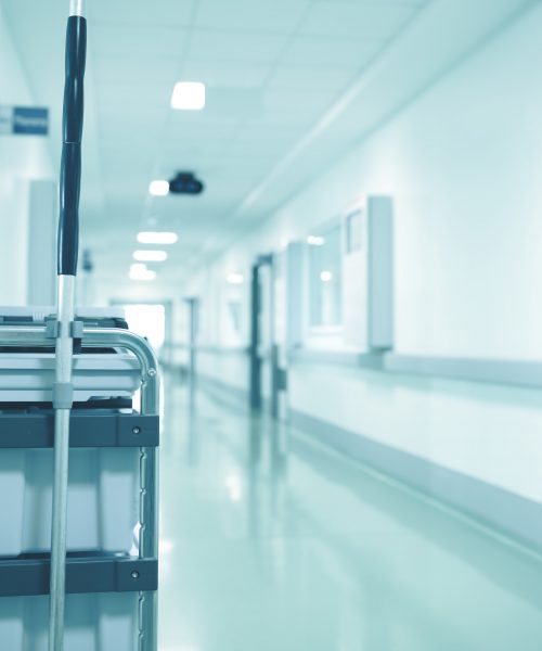 Cleaning staff cart with disinfectant solution containers in the empty hospitall hall.