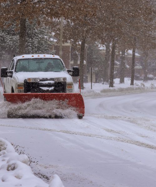 Winter service truck with snowplow removing snow clearing road maintenance in after heavy snowfall