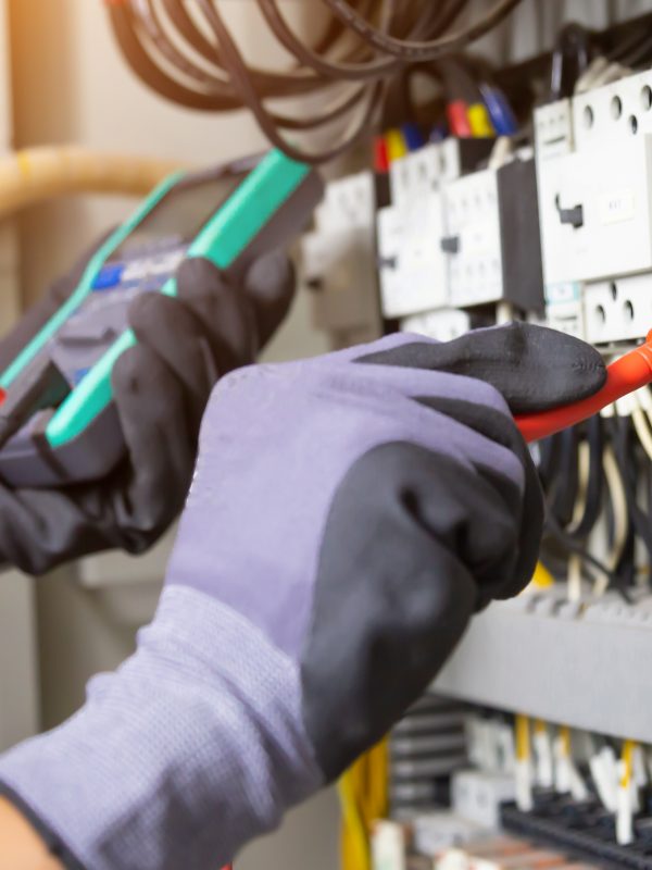 Electrician engineer tests electrical installations and wires on relay protection system. Adjustment of scheme of automation and control of electrical equipment.